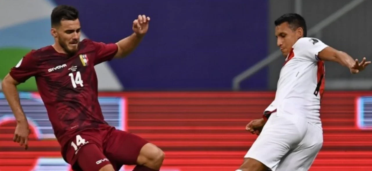 Alex Valera y Luis del Pino disputan el balón en el partido entre Venezuela y Perú / Foto: AFP