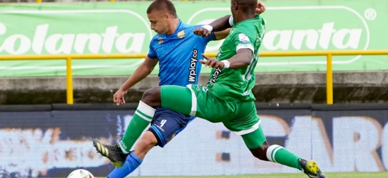 Mateo Puerta (azul) quiere centrar y Francisco Chaverra busca impedirlo - VizzorImage / Andres Rot