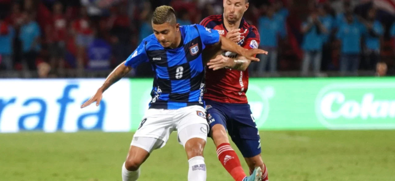 Luciano Pons (rojo) le busca arrebatar el balón a Sebastián Támara - VizzorImage / Juan Augusto Cardona