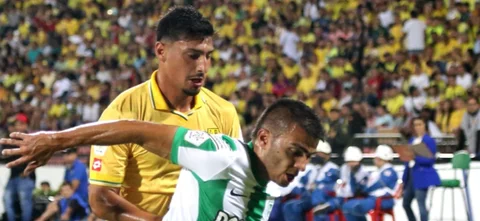 Diego Chávez (amarillo) quiere robarle el balón a Jhon Duque (verdiblanco) - VizzorImage / Jaime Moreno