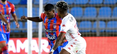 Fabián Viáfara (blanco) disputa un balón con Roberto Hinojosa (rojiazul) - VizzorImage / Miguel Vermeire